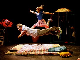 Two performers in midair above a colourful mattress