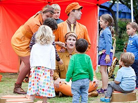 Three musicians interacting with a group of children
